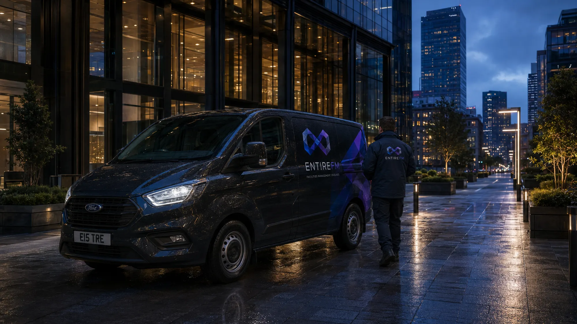 EntireFM facilities management van and engineers outside a modern glass commercial building in Manchester at dusk